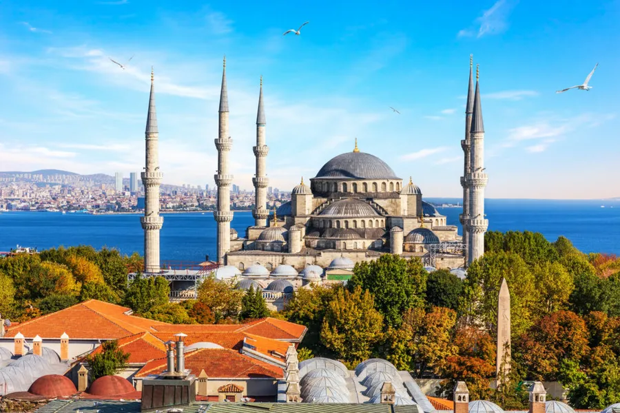 a large building with towers and a body of water with Sultan Ahmed Mosque in the background